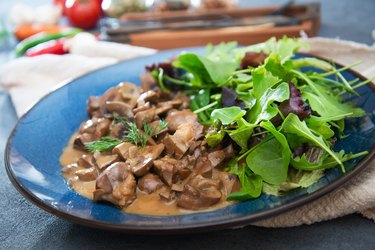 Purine-rich beef kidneys with Madeira sauce and salad on a blue plate