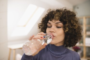 Young woman drinking water in her house to keep her blood sugar stable