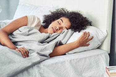 a woman sleeping in bed at home, to represent getting more deep sleep