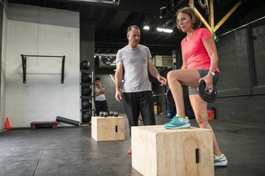 mature woman learning how to do a step-up without mistakes in the gym