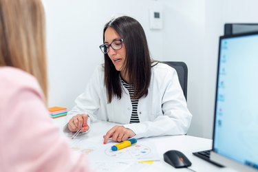 Beautiful young nutritionist woman explaining to her patient thediet he should follow to lose weight in the consultation.