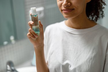 Close-up of a person holding a skin care product standing in the bathroom to represent the skin cycles