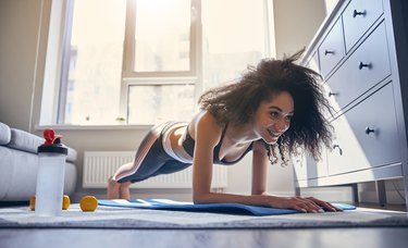 black woman with natural hair doing a plank with glute activation at home