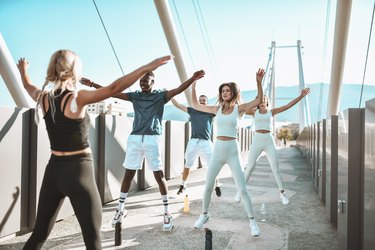 Jumping Jacks Exercise By Multiethnic Fitness Team Outside On Bridge