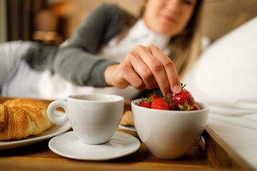 Close view of a person taking a strawberry from a bowl