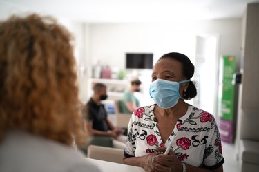 patient with face mask waiting in line at medical clinic reception