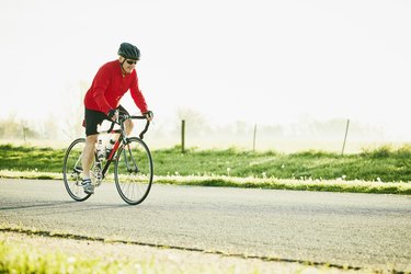 Cyclist riding road bike on a rural road at sunrise, demonstrating the proper angle of your legs while cycling.