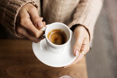 Woman hands holding espresso in white cup