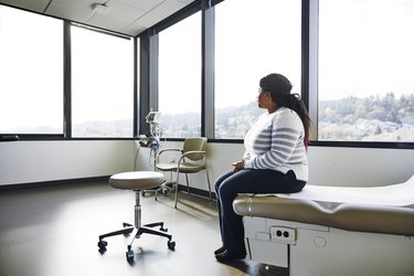 Side view of patient sitting on bed in hospital