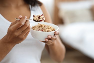 健康膳食概念。不知名的黑人女子早餐吃燕麦片配水果