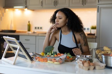 Woman reading recipe and preparing dinner at home.