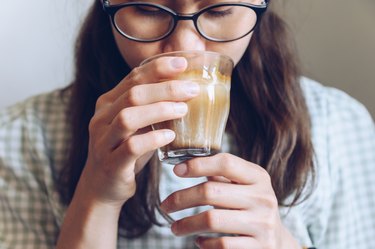 Close-up of person drinking hot latte coffee, as an example of how to reduce sugar intake