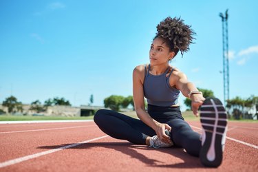 Athlete stretching on track after running workout