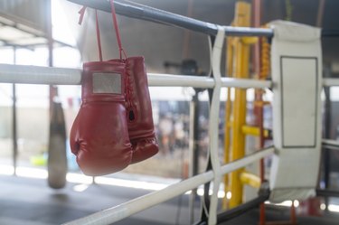 Boxing gloves sitting on the edge of a boxing ring.