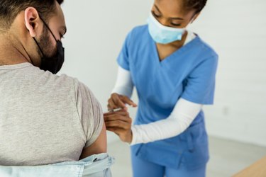 Female nurse administers COVID vaccine to male patient