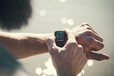 close view of a person checking their heart rate on their smartwatch during a run outdoors