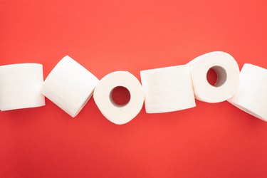 Top view of toilet paper rolls on a red background representing blood when wiping