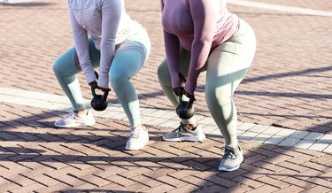 two women in city doing squats with kettlebells, a full-body kettlebell exercise