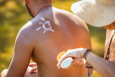 Person applying sunscreen to someone's back