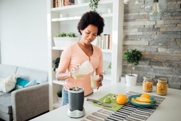 woman using blender to make a protein shake at home