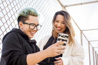 a transgender person and their friend posing for a phone selfie