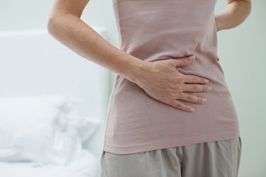 Person holding stomach and mid back in pain