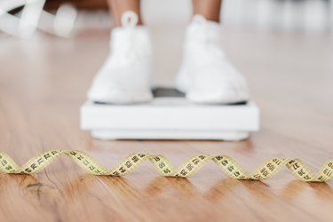 Closeup Black Woman Standing On Scales, Focus On Measure Tape