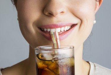 Close-up of woman's smiling mouth and soft drink