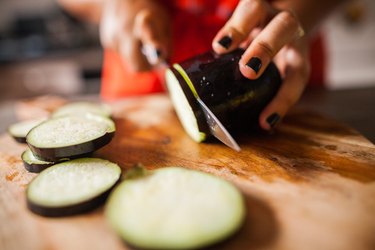 woman's hand cutting eggplant slices