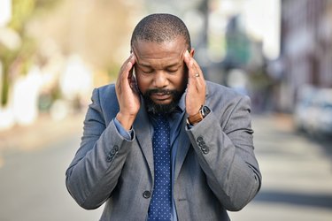 Man outside pressing his temples because he has a cold weather headache