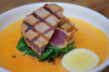 Grilled tuna fish steak with vegetable, slice of lemon and orange sauce