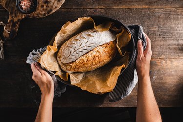 Woman holding sourdough bread in kitchen