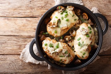 Lombardy Chicken breasts cooked with mushrooms, green onions, mozzarella cheese and parmesan closeup. horizontal top view