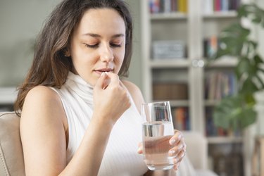 person taking antibiotics with glass of water