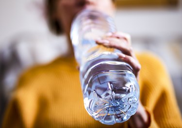 Woman drinking mineral water from expired water bottle