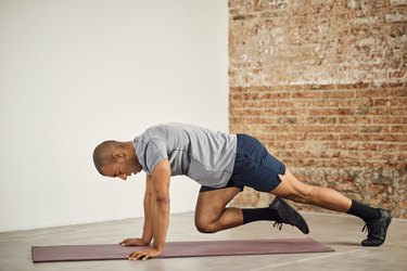 fit person with shaved head does the mountain climber to strengthen hip flexors in a studio