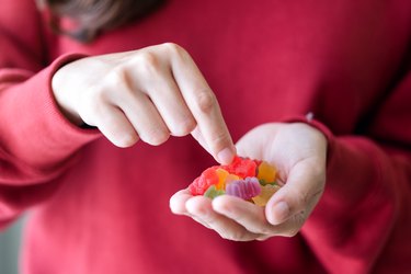 close view of a person in a red shirt holding a handful of colorful fiber gummies