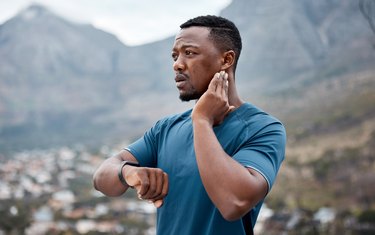 Shot of a sporty young man checking his pulse while exercising outdoors