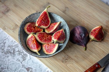 Close-up shot of a bowl of sliced figs against a wooden table