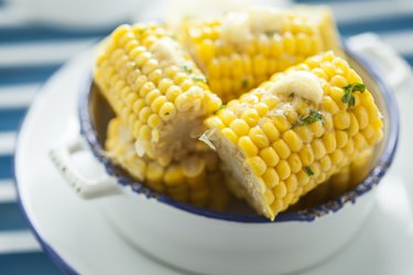 a bowl of Steamed Corn topped with butter and herbs