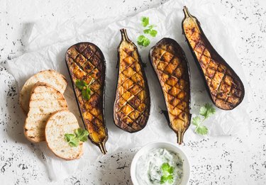 Grilled eggplant and sauce tzatziki on a light background, top view. Baked aubergine