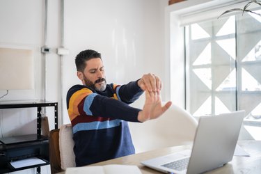 Mature man stretching while working at home