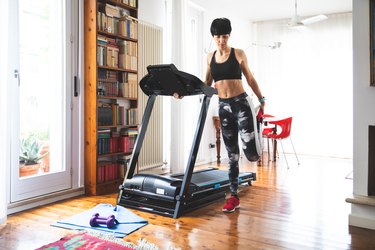 Woman stretching before using treadmill machine for a home cardio workout