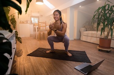 Athlete doing yoga squat for pelvic floor strengthening in bedroom