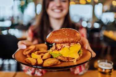 Young woman holding a plate with a burger and fries