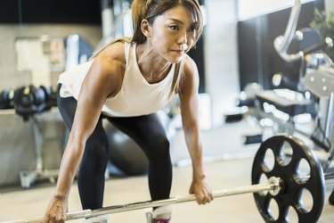 athlete with barbell working out at gym with tailbone pain from weightlifting