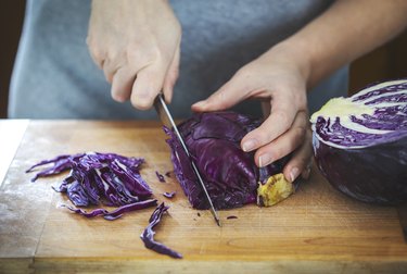 Woman's hands cutting a red cabbage.