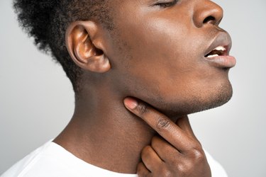 A close up photo of a person touching their jawline and neck to do an exercise to stop snoring