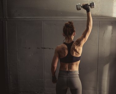 Woman doing single-arm shoulder press during her upper-body workout
