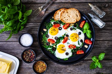 High-protein meal plan bowl of eggs and veggies on wooden table is a good breakfast for a 2,000-calorie diet for men or a man